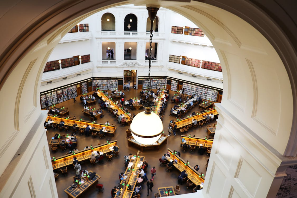 Grand reading room with tall shelves and study tables showing beautiful libraries to visit