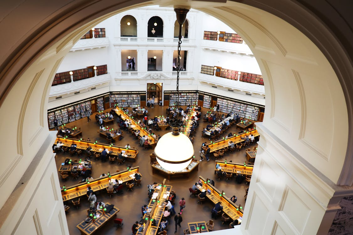 Grand reading room with tall shelves and study tables showing beautiful libraries to visit