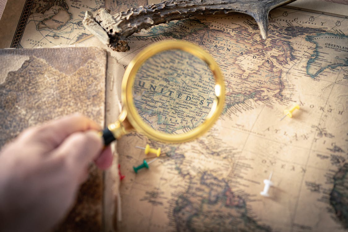 Vintage map with magnifying glass and pins showing maps that tell stories about history and place