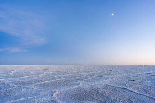 Vast white salt flats under a blue sky, an example of otherworldly places on Earth