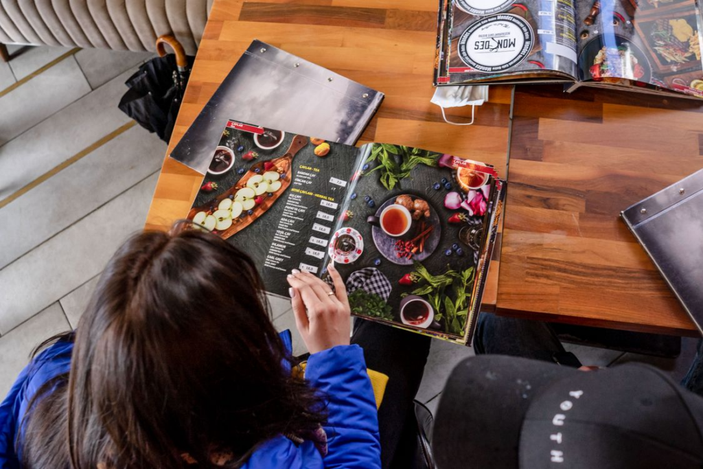 Diner reading a restaurant menu illustrating the origins of food names and everyday dishes